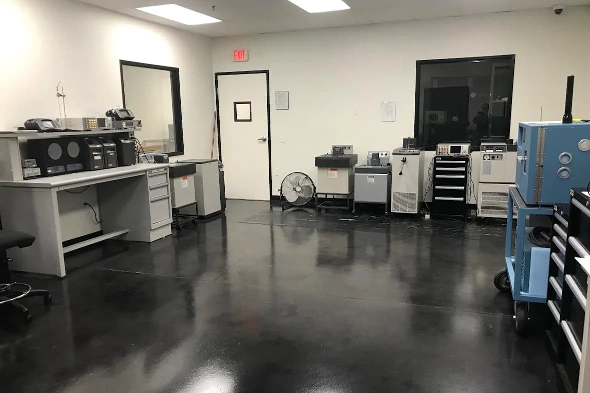 American Gage temperature and humidity laboratory with calibration baths, temperature sources, and environmental chambers along the wall and reference readouts on the bench