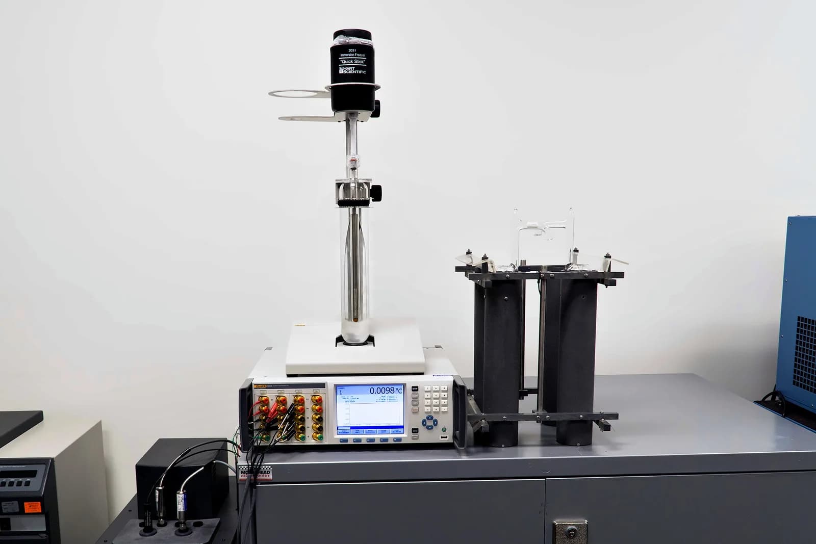 Triple point of water cell in a Hart Scientific 2031 immersion freezer above a Fluke 1594A Super Thermometer reading 0.0098 °C, with the triple-point maintenance bath and SPRT holders alongside, in the American Gage temperature laboratory